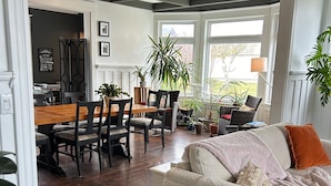 A modern living room with a sofa, dining area with chairs and a table, and a kitchen in the background. - La Casa d'Alexina (Cap-Chat)