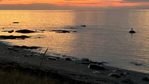 A beach with calm water, rocks, and a buoy. - La Casa d'Alexina (Cap-Chat)