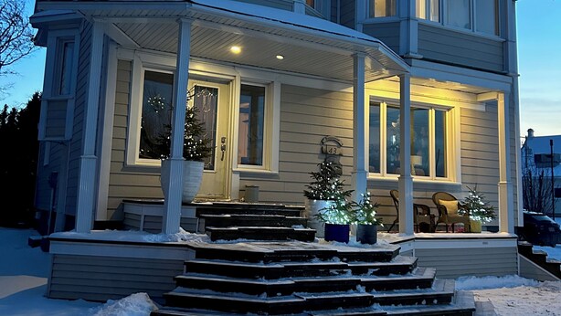 A two-story house with a porch, steps leading up to the entrance, and a mailbox. - La Casa d'Alexina (Cap-Chat)