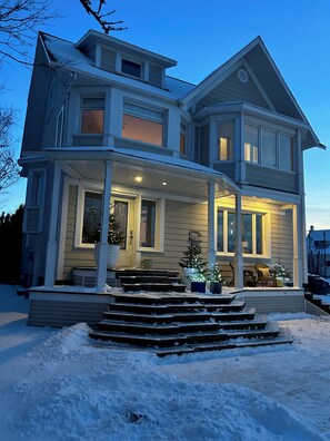 A two-story house with a porch, steps leading up to the entrance, and a mailbox.