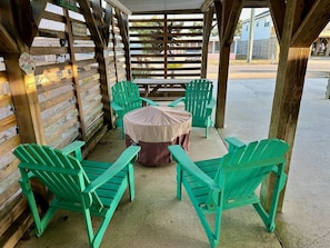 A covered outdoor seating area with wooden walls and green Adirondack chairs. - Happy Hour: Pet Friendly, Oceanside, Close to the Beach and Perfect for Families! (Kill Devil Hills)