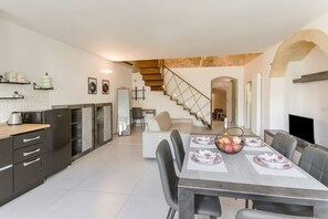 Eine moderne Küche mit dunklen Schränken, ein Essbereich mit Tisch für vier Personen und eine Treppe, die in ein Obergeschoss führt.