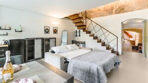 Una habitación de hotel moderna con una cama, una mesa de comedor, una zona de cocina y una escalera.