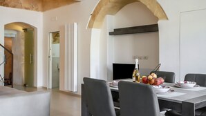 Un comedor moderno con una mesa lista para dos personas, una botella de vino y un frutero.