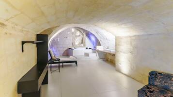 A modern interior with a stone archway leading to a bathroom with a bathtub and a vanity.