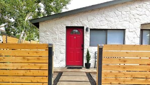 Ein Haus mit roter Tür, Steinaußenwand und einem kleinen Blumentopf davor.