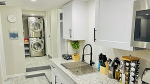 Eine moderne Küche mit Granit Arbeitsplatten, einem eingebauten Herd und einem Spülbecken. Darüber befindet sich eine Mikrowelle, und ein Geschirrgestell ist zu sehen.