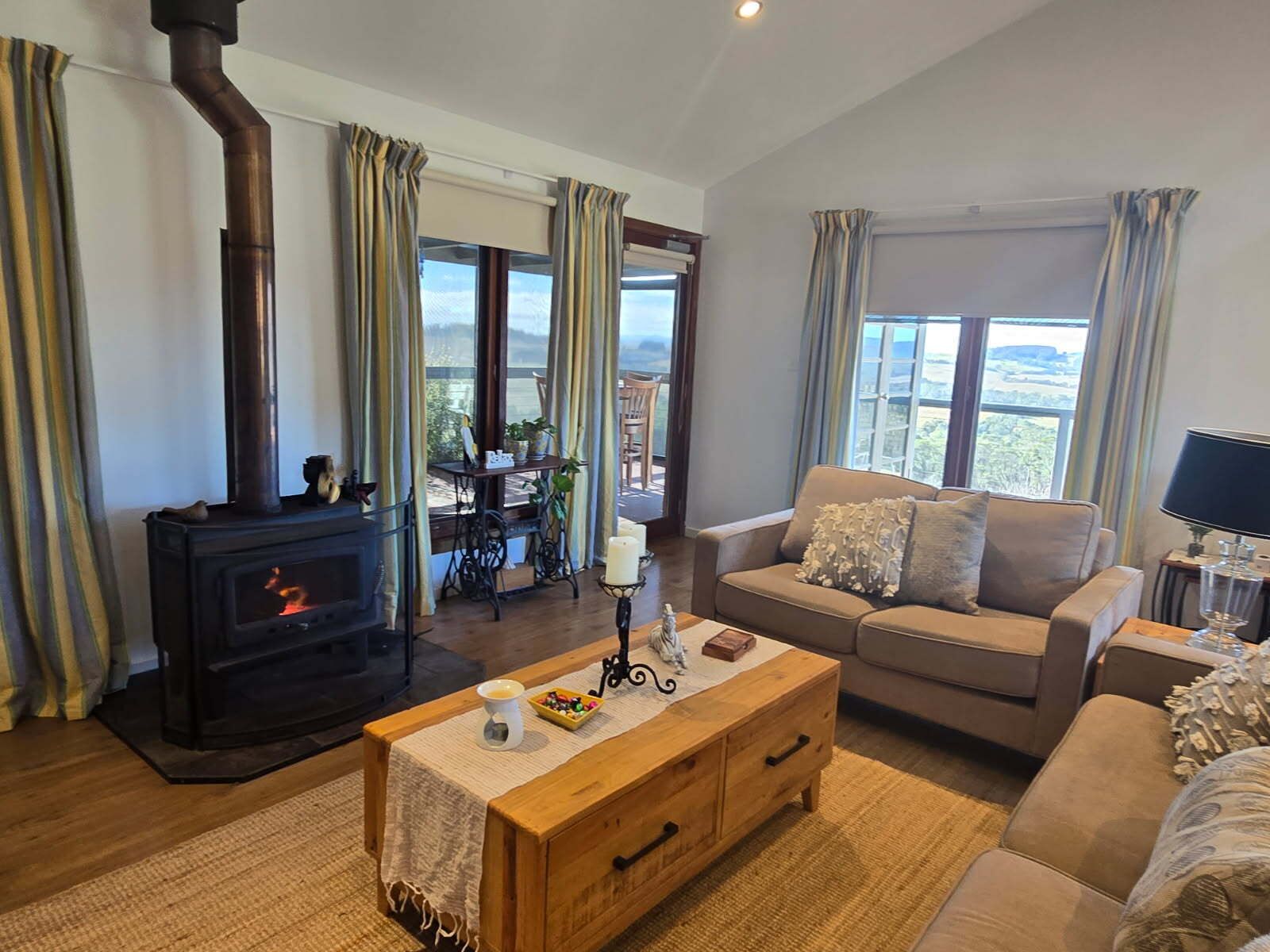 A cozy living room with a fireplace, a sofa, a coffee table, and a view of the outdoors.