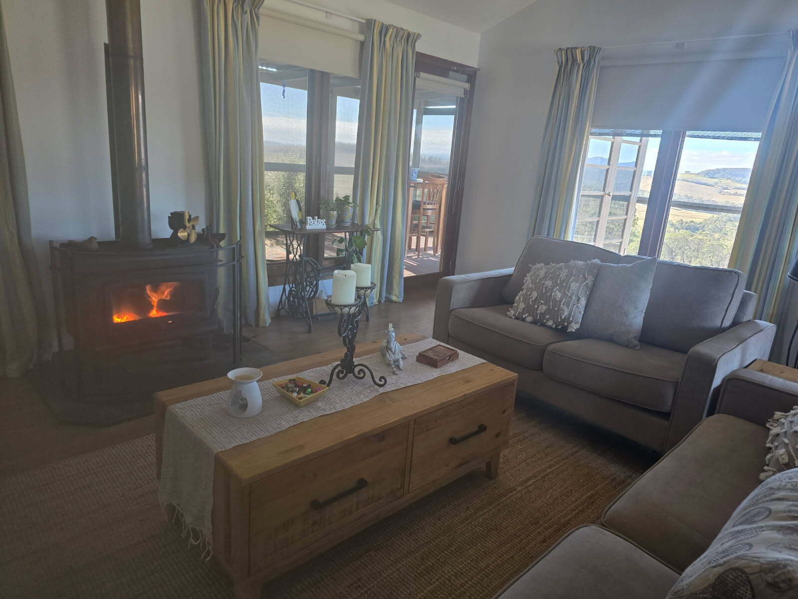A cozy living room with a fireplace, a sofa, a coffee table, and a view of the outdoors.