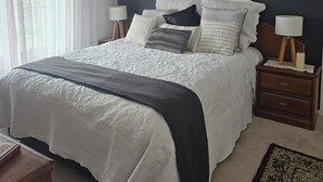 A bedroom with a bed, bedside tables, a lamp, a rug, and a window with curtains.