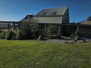 Una casa moderna con una terraza grande, un espacio exterior cubierto y un césped bien cuidado.