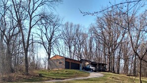 A two-story house with a garage, surrounded by trees and a grassy yard.