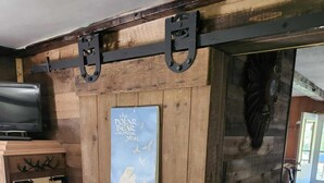Un intérieur rustique avec un mur en bois, un calendrier, une télévision et un banc.