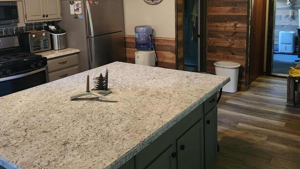 A kitchen with granite countertops, a built-in oven, a refrigerator, and a ceiling fan.