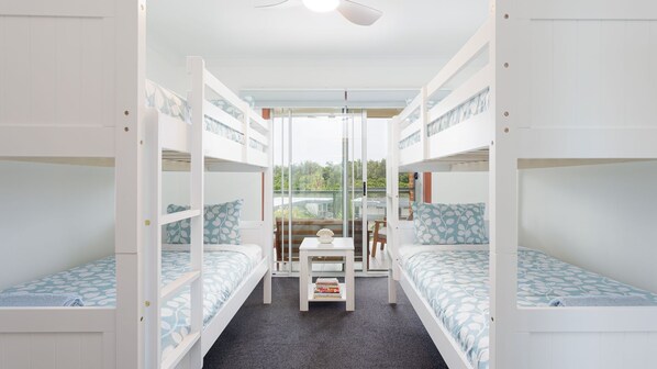 Un dormitorio con literas, una pequeña mesa con libros y vistas al exterior a zonas verdes.