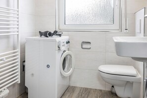 A compact, modern bathroom with a built-in washing machine, a toilet, and a sink. - 50165 Apartment Seestern - Small, but totally romantic: On approx. 45 sqm (Carolinensiel)
