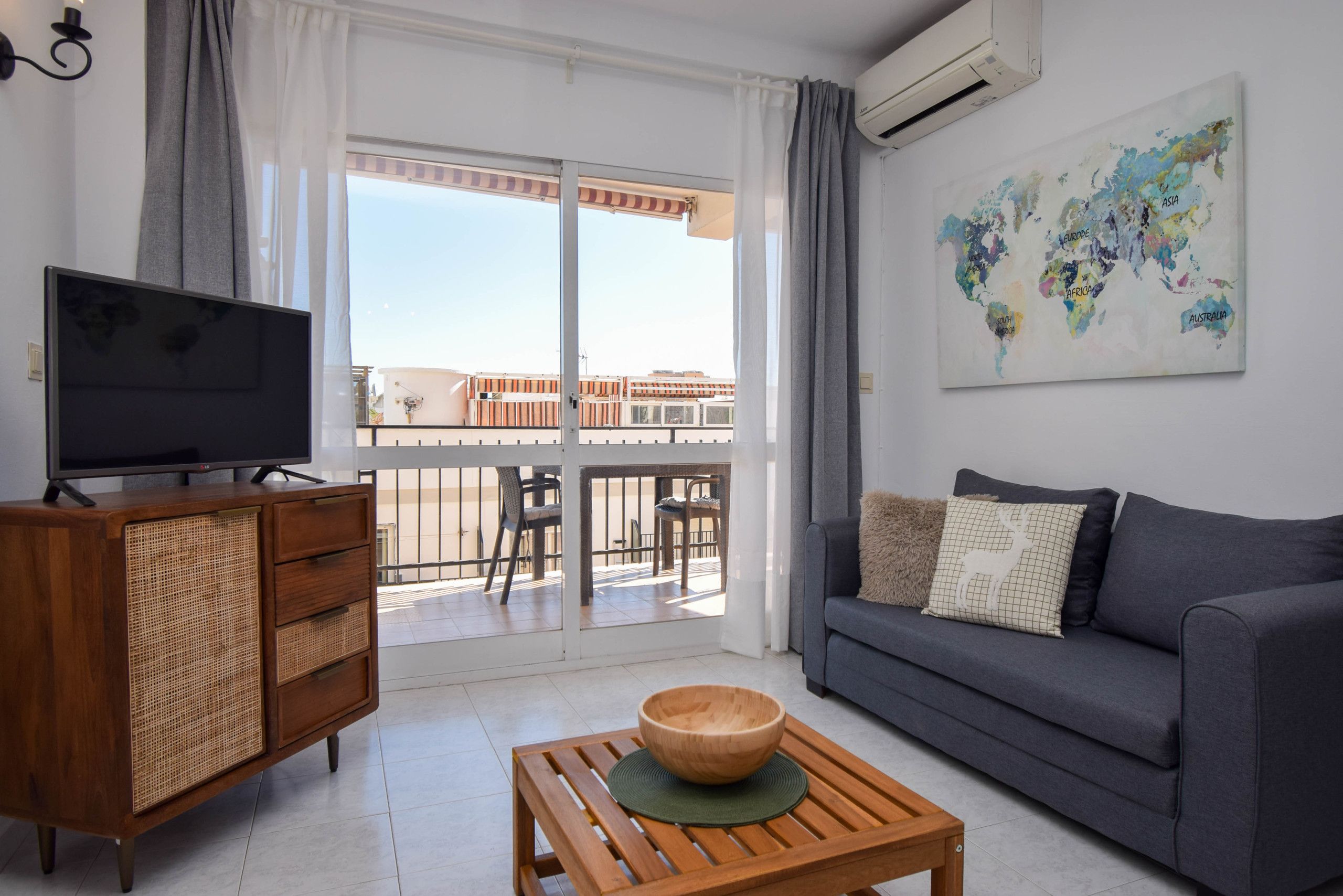 A living room with a television, wooden coffee table, sofa, and a world map artwork.
