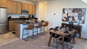 Een moderne keuken met houten kastjes, roestvrijstalen apparatuur en een centraal eiland met barstoelen.