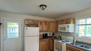 Una cocina con armarios de madera, un refrigerador blanco, un microondas, una estufa y un lavamanos.