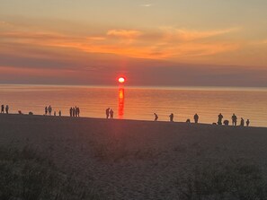 A sunset over a beach with people silhouetted against the sky.