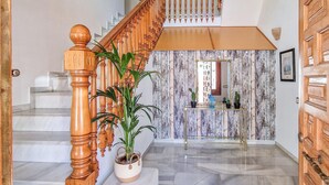 A staircase with wooden balusters, a potted plant, a console table with a mirror, and a door with a decorative panel. - Nice apartment in Malaga with swimming pool (Malaga)