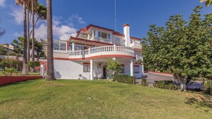 A two-story house with a balcony, a well-maintained lawn, and a clear blue sky. - Nice apartment in Malaga with swimming pool (Malaga)