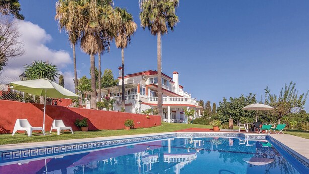 A pool area with a clear blue pool, white lounge chairs, and palm trees. - Nice apartment in Malaga with swimming pool (Malaga)
