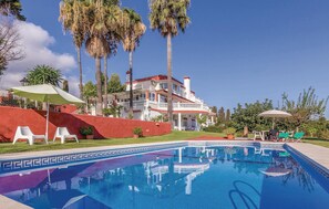 A pool area with a clear blue pool, white lounge chairs, and palm trees. - Nice apartment in Malaga with swimming pool (Malaga)