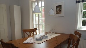 A dining area with a wooden table, chairs, and a hanging light fixture. - Vacation at Hüs Dikstian in Alkersum - Hüs Dikstian (Alkersum)