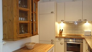 A kitchen with wooden cabinets, a built-in oven, and a countertop with a bowl. - Vacation at Hüs Dikstian in Alkersum - Hüs Dikstian (Alkersum)