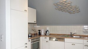 A modern kitchen with white cabinets, stainless steel appliances, and a decorative fish mural on the wall.