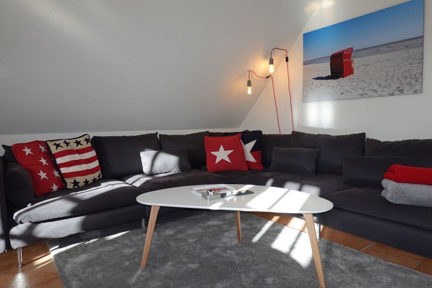 Ein modernes Wohnzimmer mit einer Eckcouch, einem weißen Couchtisch und einem Strandbild an der Wand.