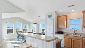 A spacious kitchen with a large island, wooden cabinets, and a view of the outside. - 4 br Ocean view, beach, pool! (Rodanthe)