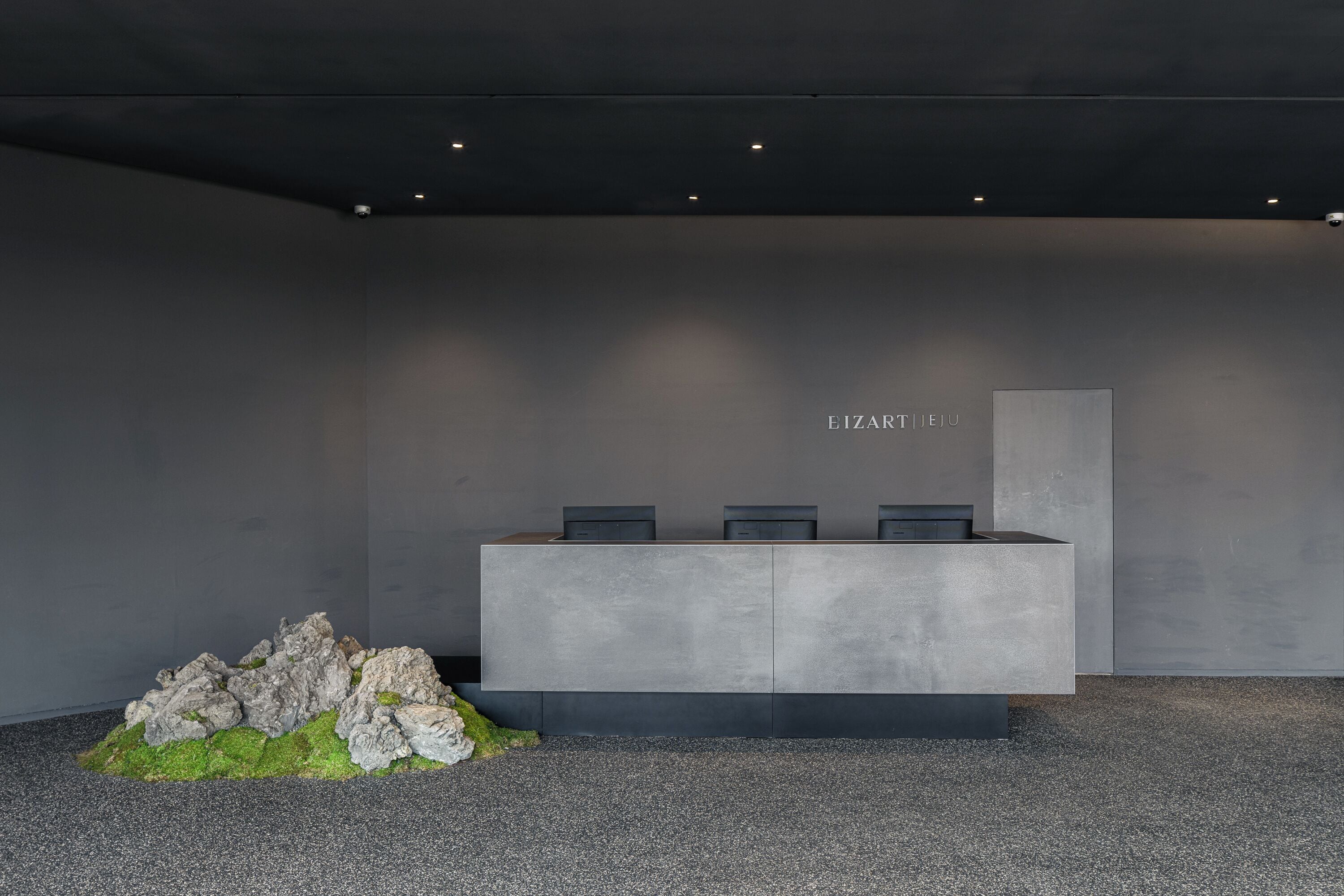 A reception desk with a minimalist design, a nameplate, and a small rock formation.