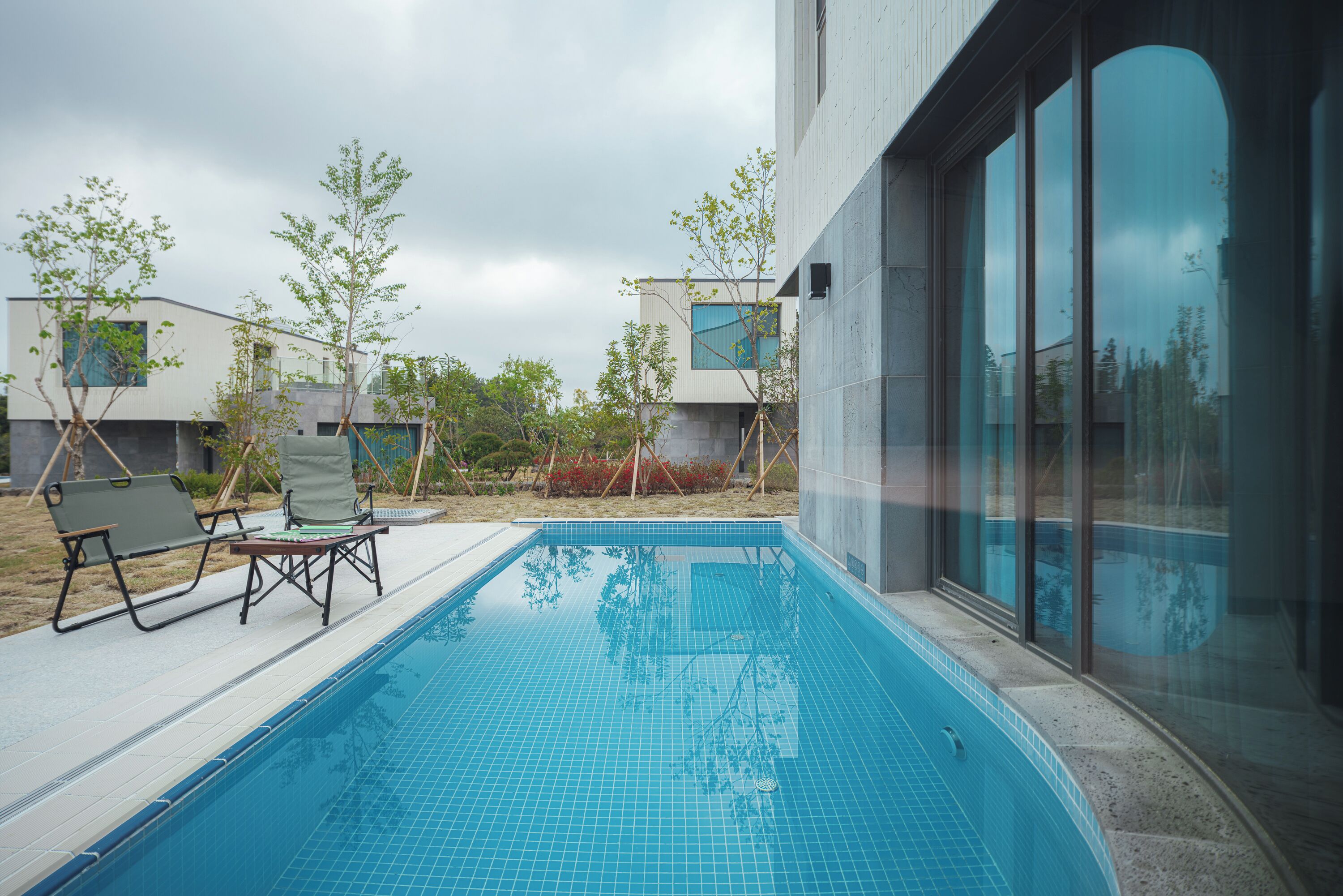 A modern outdoor swimming pool with lounge chairs and a clear view of the surrounding buildings.