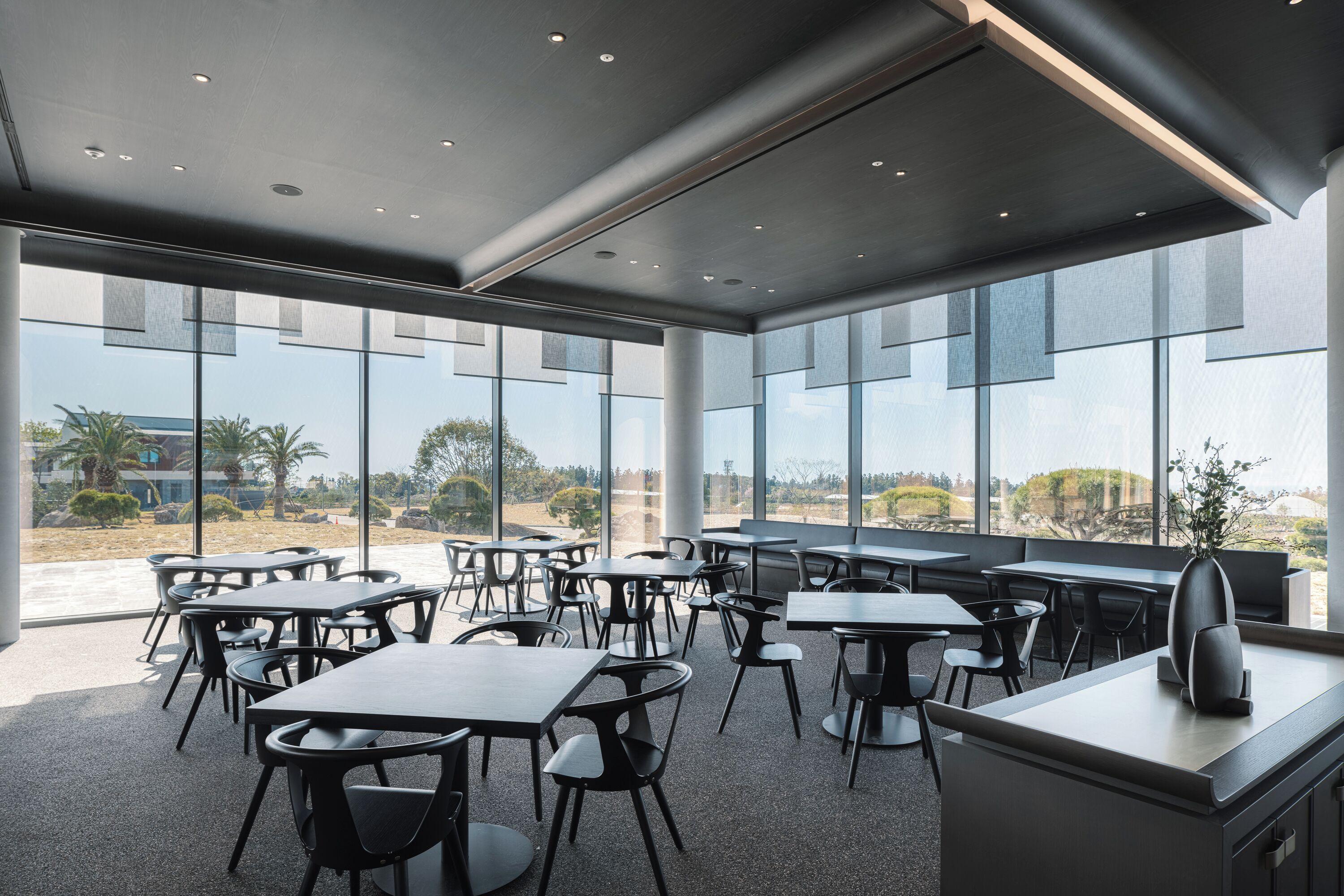 Un comedor moderno con mesas y sillas, ventanas amplias y vistas al exterior.