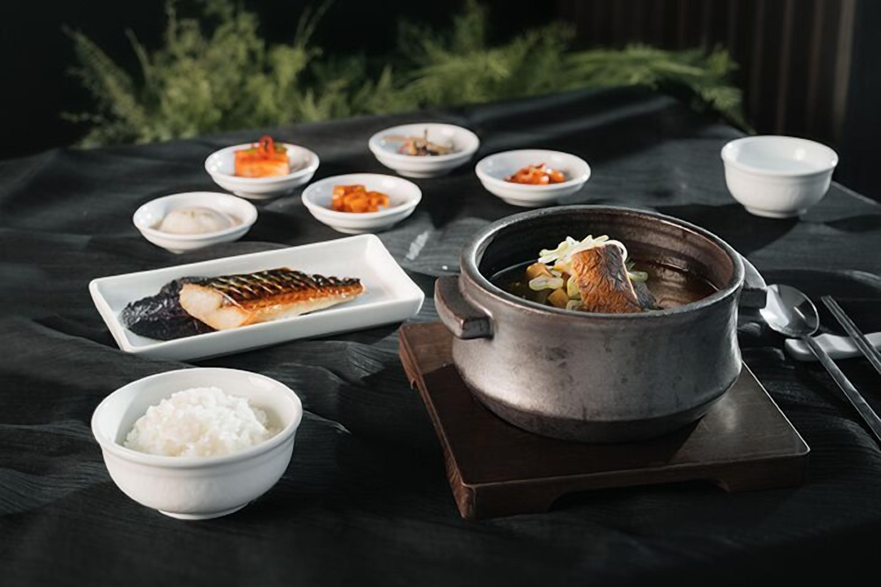 A traditional Japanese meal setup with a pot of soup, rice, and various side dishes on a table.
