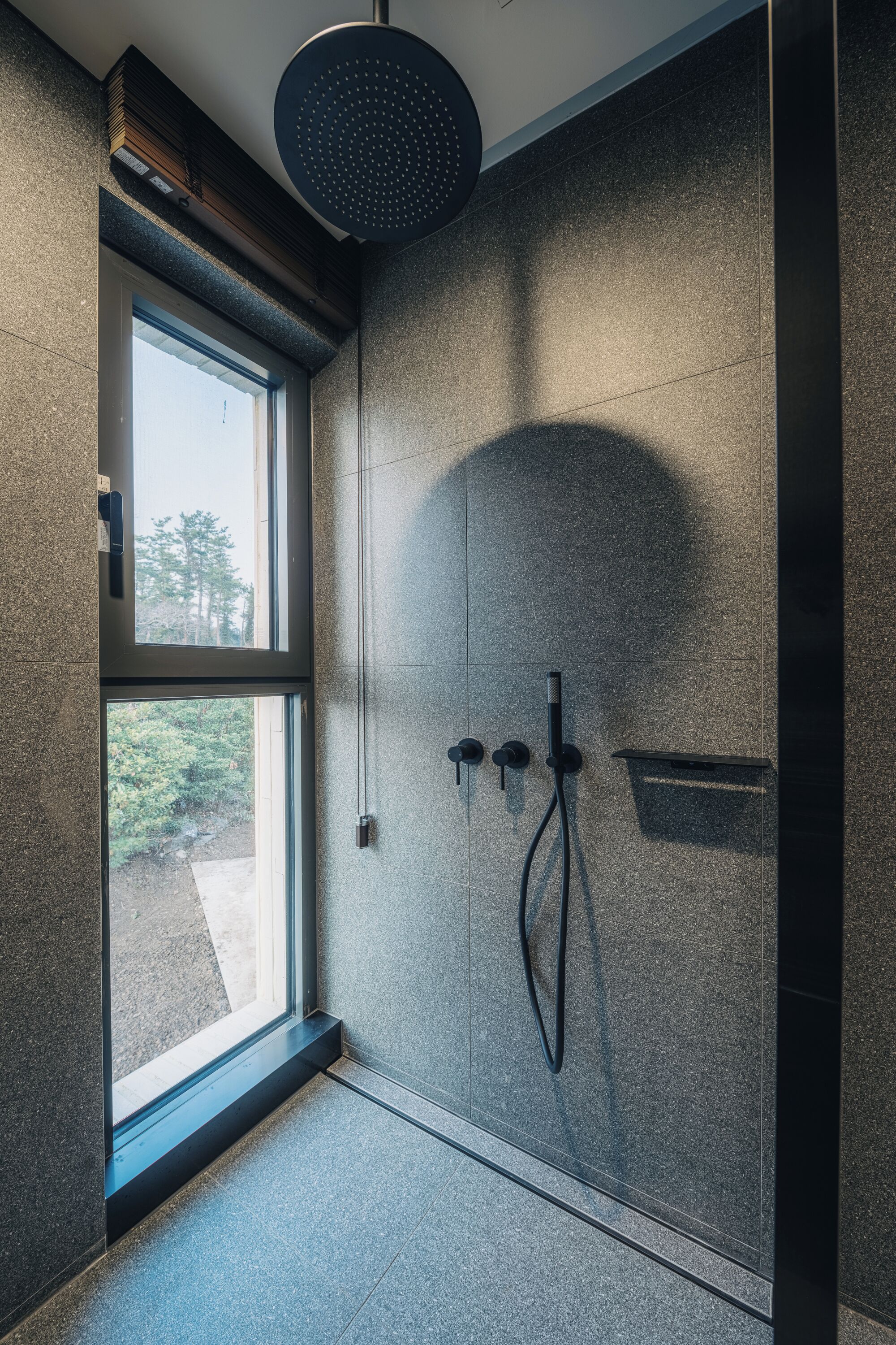A modern shower with a rain showerhead, a handheld showerhead, and a handheld shower attachment.