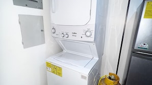 Ein kleiner Hauswirtschaftsraum mit einer Waschmaschine und einem Trockner, einem Gasflasche und einem Kühlschrank.