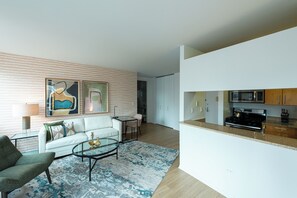 Una sala de estar moderna con un sofá, un sillón, una mesa de centro y una obra de arte en la pared.