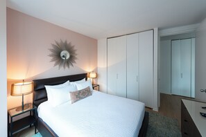 Una habitación de hotel con cama, dos lámparas de noche, un espejo en la pared y un armario.
