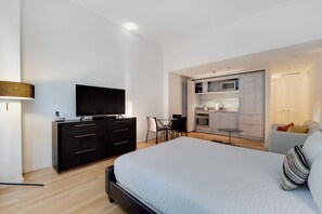 Une chambre d’hôtel moderne dotée d’un grand lit, d’une télévision à écran plat, d’un bureau et d’une kitchenette.