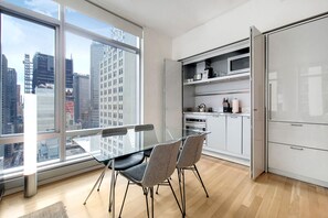 A modern kitchen with a glass dining table and chairs, a microwave, and a refrigerator.