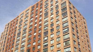 Un edificio alto con una fachada de ventanas y balcones, probablemente residencial u oficinas.