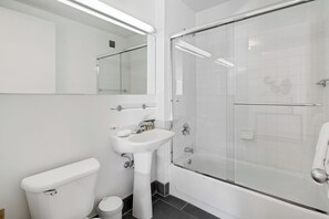 Moderni kylpyhuone, jossa on wc, pesuallas ja lasiseinällä varustettu suihku.