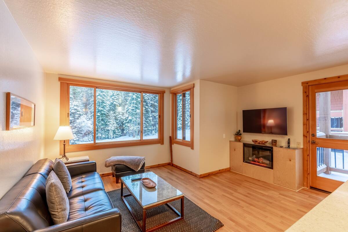 A living room with a sofa, a coffee table, a TV, and a fireplace.