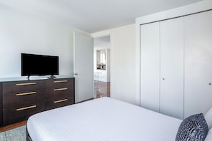 A bedroom with a bed, a dresser with drawers, a television on top, and a wardrobe.