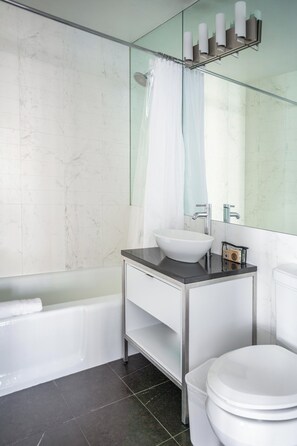 Ein modernes Badezimmer mit einer weißen Badewanne, einem Waschbecken mit Spiegel darüber und einer Toilette.