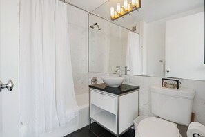 A modern bathroom with a white sink, a toilet, and a shower.