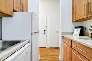 A kitchen with wooden cabinets, a white refrigerator, and a countertop with a coffee maker.